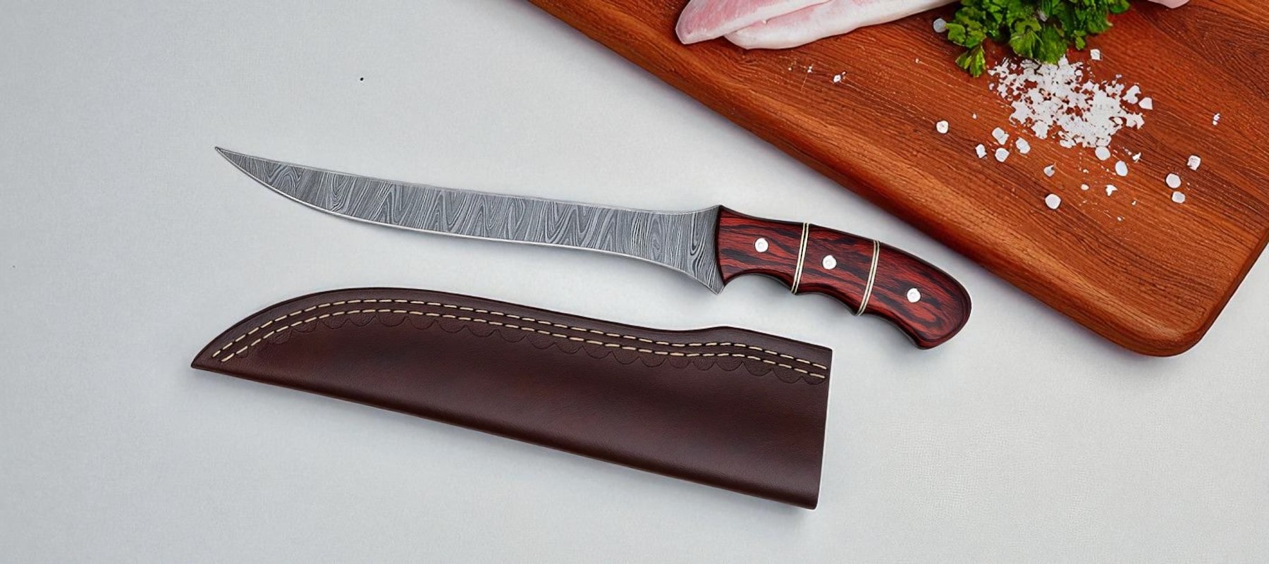 Fillet knife with leather sheath on a white surface with a wooden cutting board in the background.